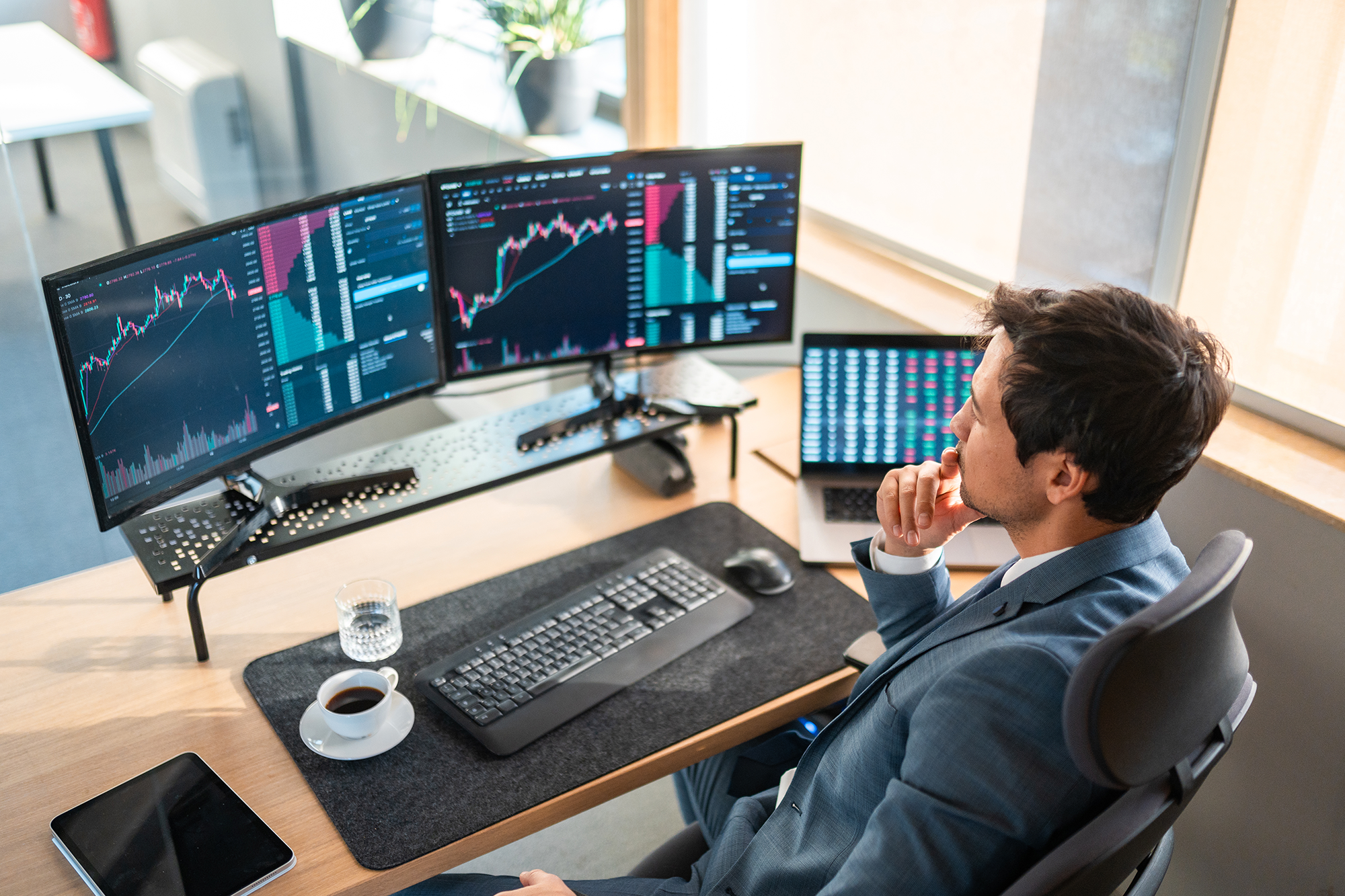 business professional looking at stock trends on two computer monitors