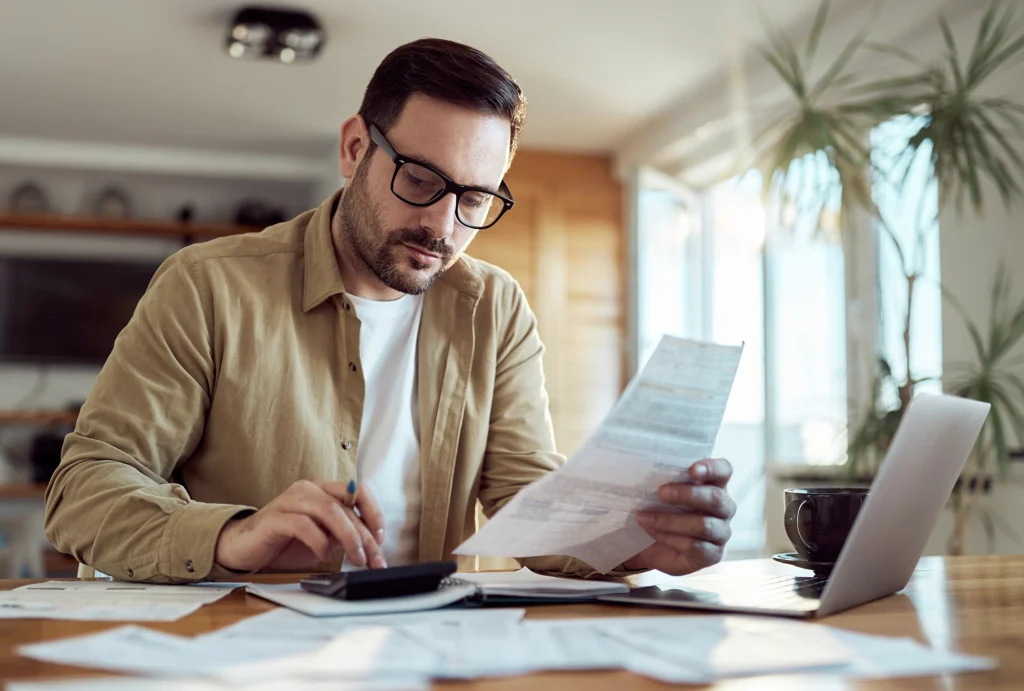 Man in his kitchen looking at his finances and investments