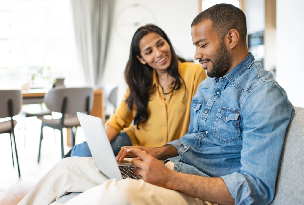 young husband and wife sitting on couch, looking at financials