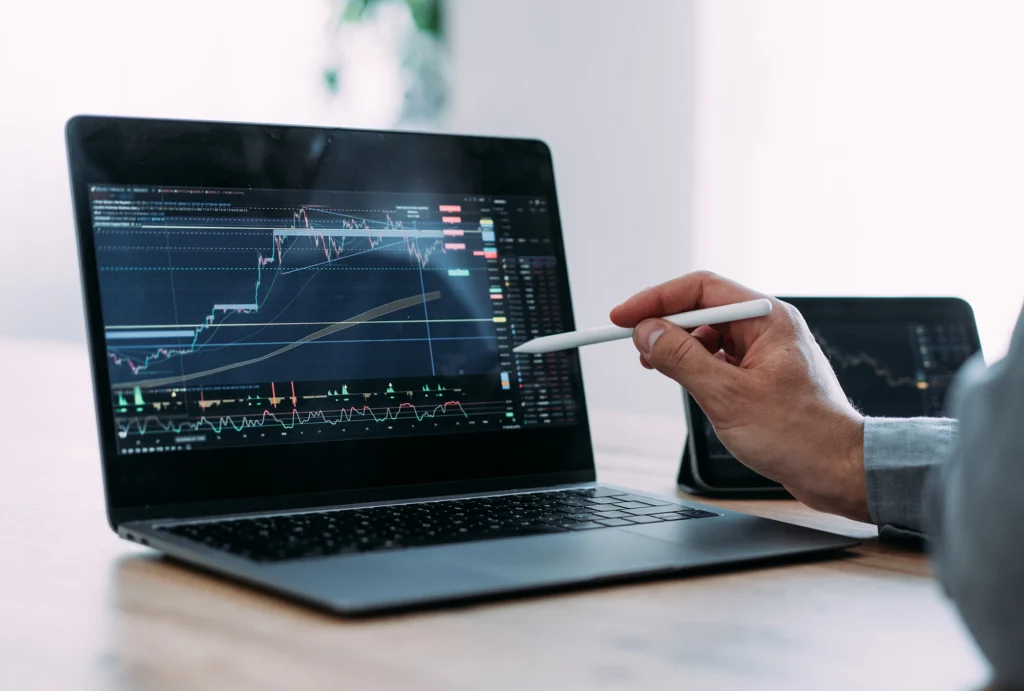 advisor using stylus to point at computer screen showing stocks