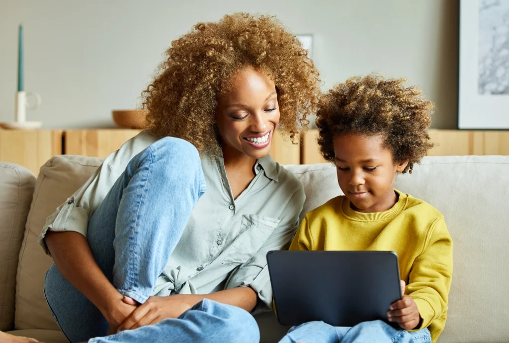 Mother sitting with son on the couch, looking at laptop