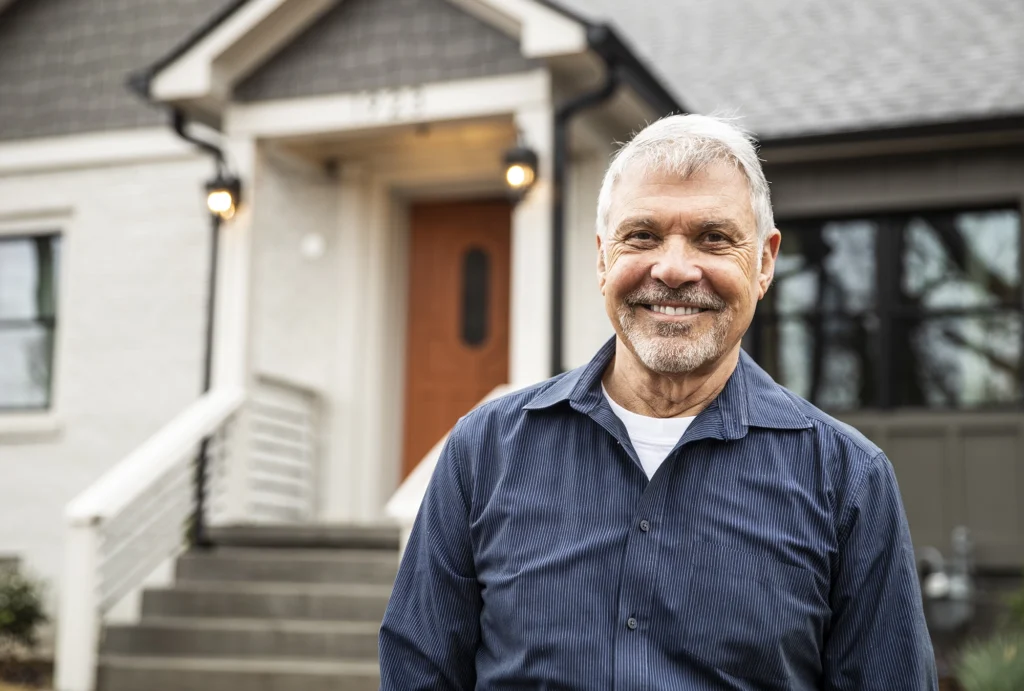man standing in front of house smiling