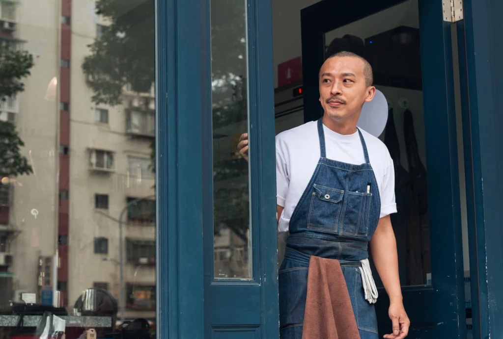 Waiter standing in doorway of restaurant looking down the street